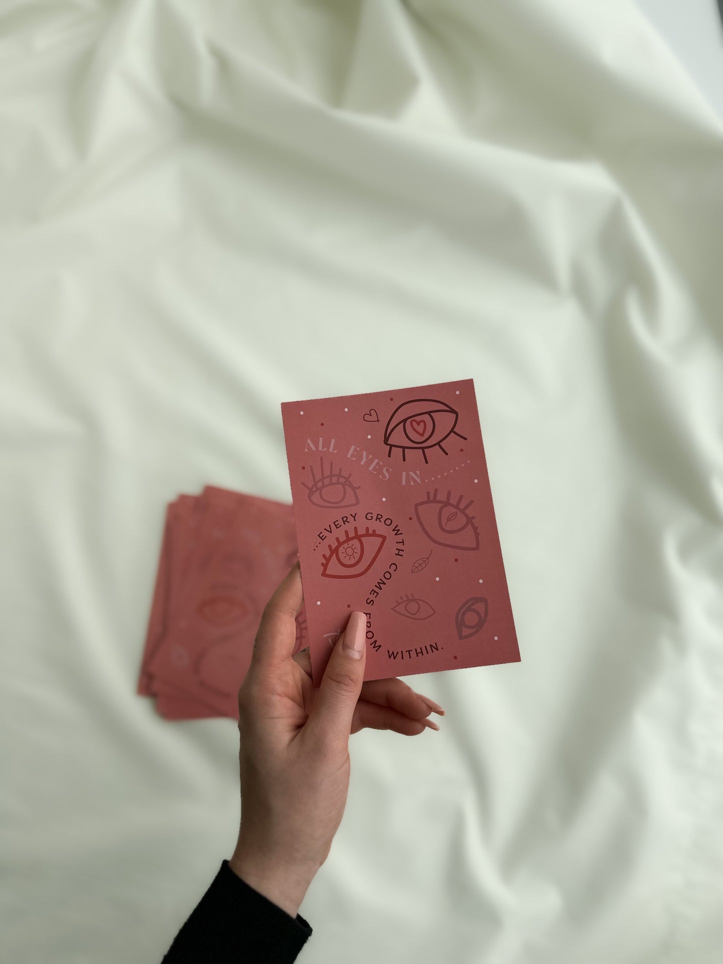 Eine Postkarte in der Hand mit Augen und "Every growth comes from within" Aufdruck