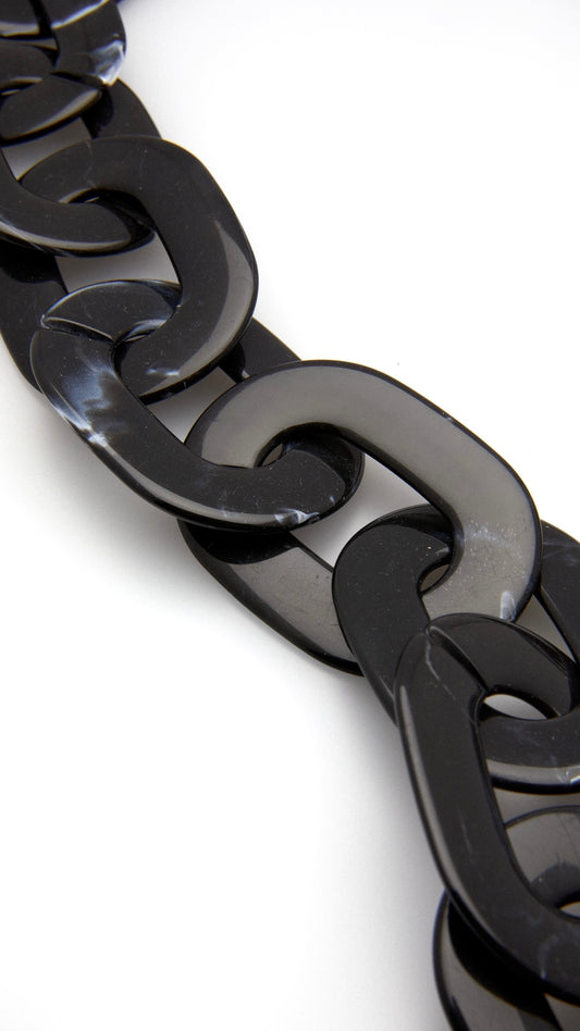 Nahaufnahme einer Brillenkette bestehend aus großen, schwarzgemusterten, runden Gliedern
