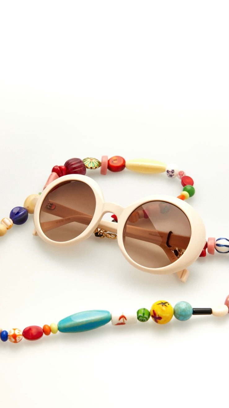 runde weiße Brille, an der eine Brillenkette aus bunten Perlen befestigt ist