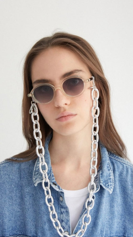 Frau trägt eine runde Brille mit einer Brillenkette aus silbernen, runden, großen Kettengliedern